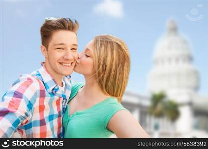 travel, tourism, technology, love and people concept - smiling couple kissing and taking selfie over washington white house background