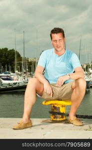 Travel tourism vacation and people concept. Fashion portrait of handsome man on pier against white yachts in port