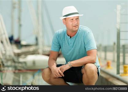 Travel tourism vacation and people concept. Fashion portrait of handsome man on pier against yachts in port