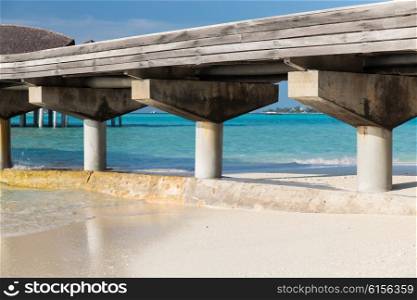 travel, tourism, vacation and summer holidays concept - bridge on stilts on exotic resort beach