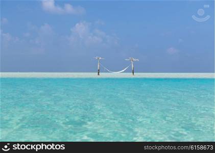 travel, tourism, vacation and summer holidays concept - hammock in water on maldives beach