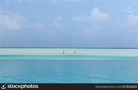 travel, tourism, vacation and summer holidays concept - hammock in water on maldives beach