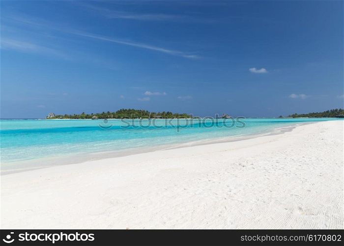 travel, tourism, vacation and summer holidays concept - maldives island beach with palm tree and villa