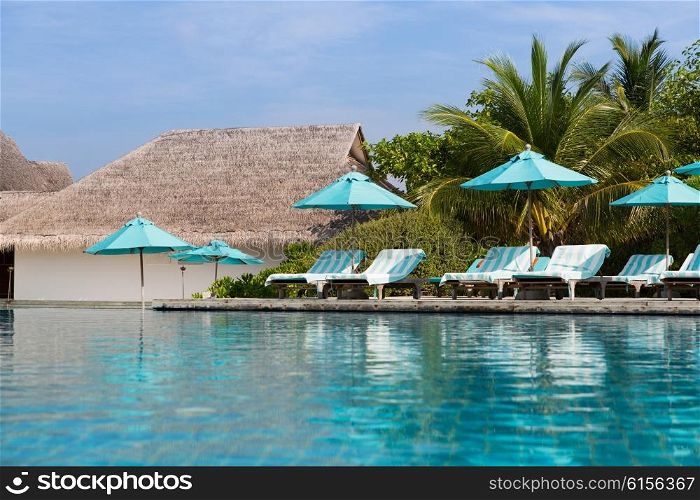travel, tourism, vacation and summer holidays concept - parasol and sunbeds over sea and sky on maldives beach