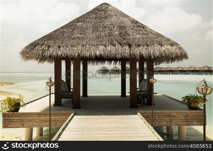 travel, tourism, vacation and summer holidays concept - patio or terrace with canopy on maldives beach sea shore