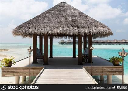travel, tourism, vacation and summer holidays concept - patio or terrace with canopy on maldives beach sea shore