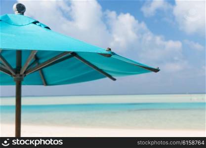 travel, tourism, vacation, beach and summer holidays concept - parasol over blue sky and beach