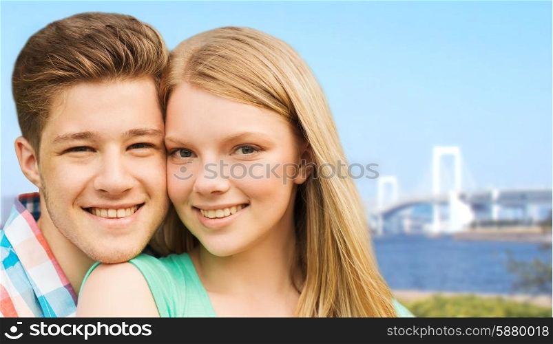 travel, tourism, vacation, people and love concept - smiling couple hugging over rainbow bridge in tokyo and river background
