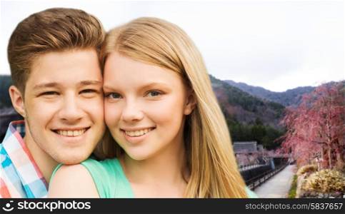 travel, tourism, vacation, people and love concept - smiling couple hugging over asian village landscape background