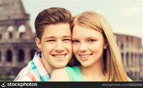 travel, tourism, vacation, people and love concept - smiling couple hugging over coliseum background