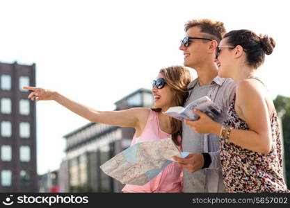 travel, tourism, vacation, summer and people concept - smiling friends with map and city guide pointing finger outdoors