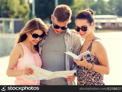 travel, tourism, vacation, summer and people concept - smiling friends with map and city guide outdoors