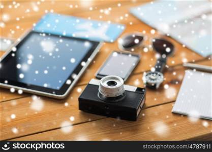 travel, tourism, winter holidays and technology concept - retro film camera, gadgets and personal stuff over snow