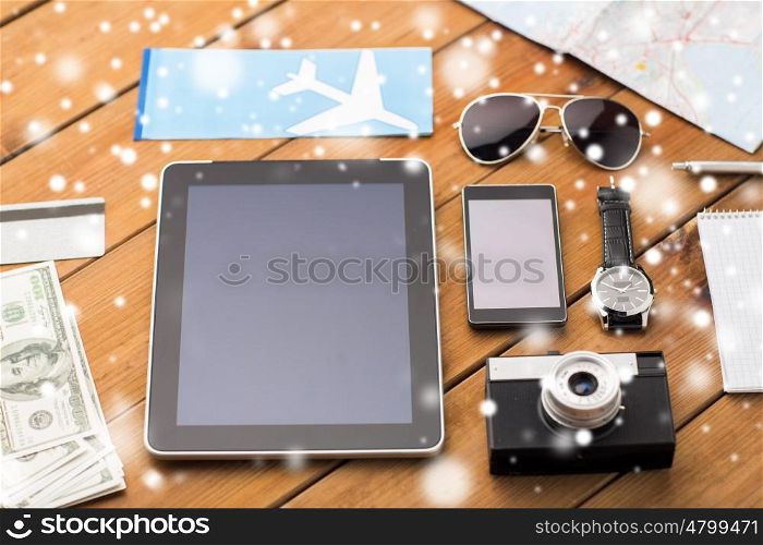 travel, tourism, winter holidays and technology concept - smartphone with tablet pc computer, airplane ticket and personal stuff over snow