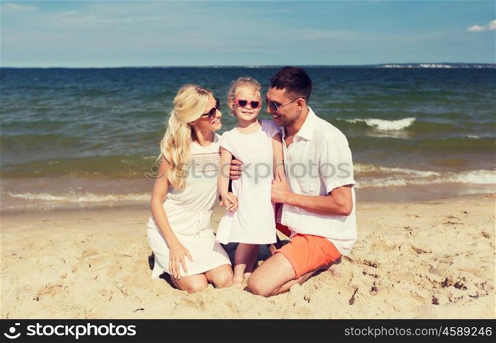 travel, vacation, adoption and people concept - happy family with little girl in sunglasses talking on summer beach