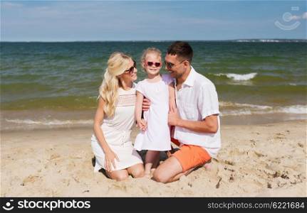 travel, vacation, adoption and people concept - happy family with little girl in sunglasses talking on summer beach
