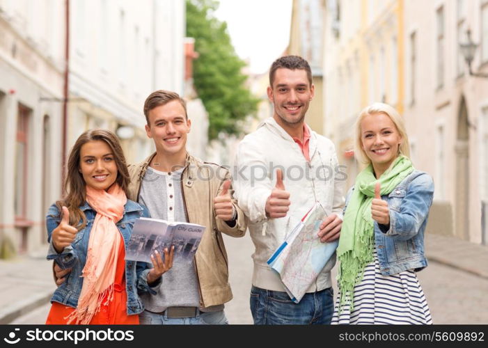 travel, vacation and friendship concept - group of smiling friends with city guide and map showing thumbs up in the city