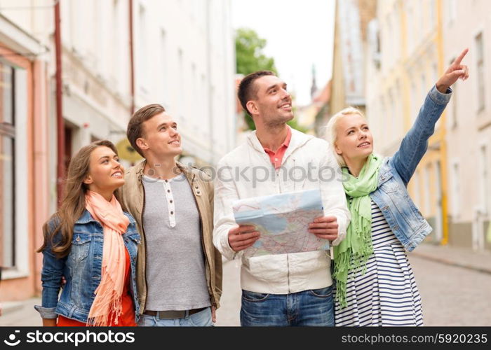 travel, vacation and friendship concept - group of smiling friends with city map exploring city