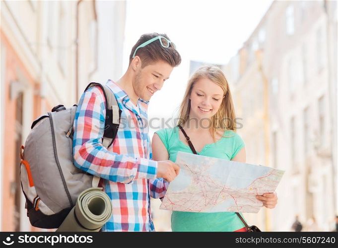 travel, vacation and friendship concept - smiling couple with map and backpack in city