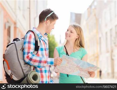 travel, vacation and friendship concept - smiling couple with map and backpack in city