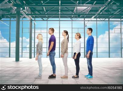 travel, vacation and people concept - group of men and women from side over airport terminal window and sky background