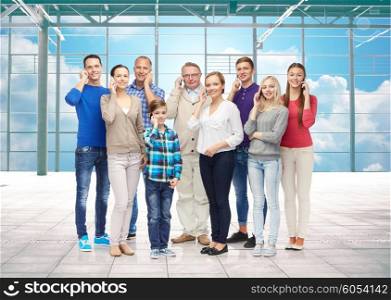 travel, vacation, communication and people concept - happy people or big family calling on smartphones over airport terminal window and sky background