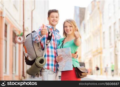 travel, vacation, gesture and friendship concept - smiling couple with map and backpack showing thumbs up in city
