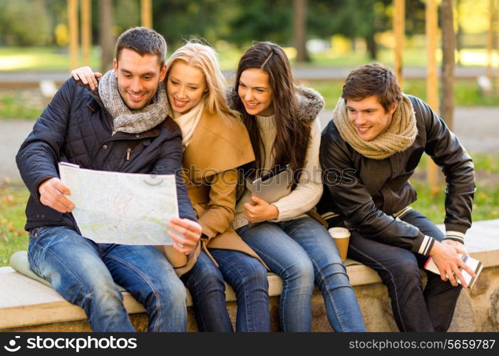 travel, vacation, people, tourism and friendship concept - group of smiling friends sitting with tablet pc computer city guide and map in park