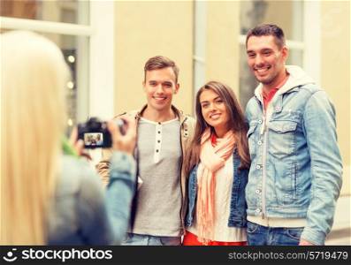 travel, vacation, technology and friendship concept - girl picturing group of friends in city