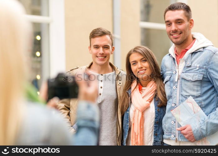 travel, vacation, technology and friendship concept - girl picturing group of friends with map in city