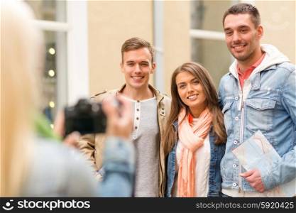 travel, vacation, technology and friendship concept - girl picturing group of friends with map in city