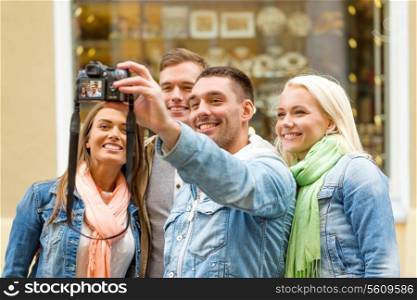 travel, vacation, technology and friendship concept - group of smiling friends making selfie with digital camera outdoors