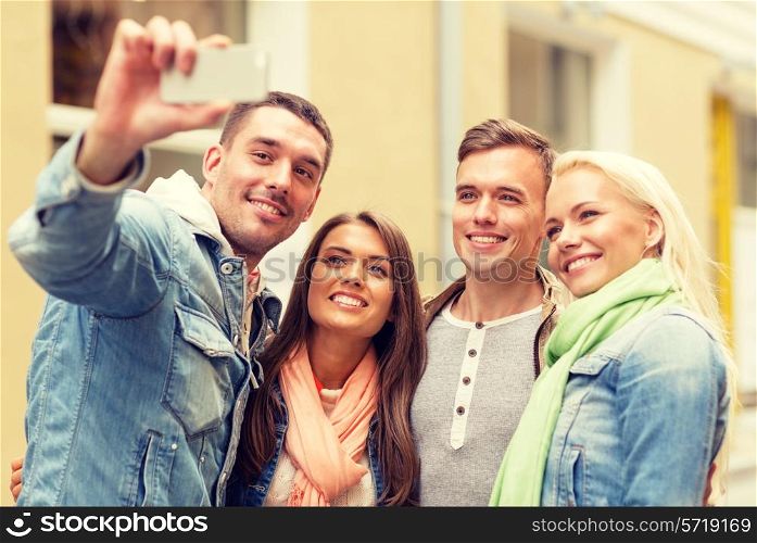 travel, vacation, technology and friendship concept - group of smiling friends making selfie with smartphone camera outdoors