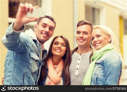 travel, vacation, technology and friendship concept - group of smiling friends making selfie with smartphone camera outdoors