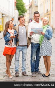 travel, vacation, technology and friendship concept - group of smiling friends with map and photocamera exploring city