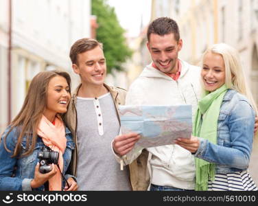 travel, vacation, technology and friendship concept - group of smiling friends with map and photocamera exploring city