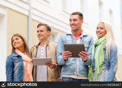 travel, vacation, technology and friendship concept - group of smiling friends with tablet pc computers in the city