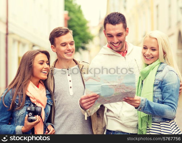 travel, vacation, technology and friendship concept - group of smiling friends with map and photocamera exploring city