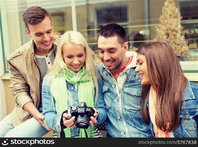 travel, vacation, technology and friendship concept - group of smiling friends with digital photocamera in the city