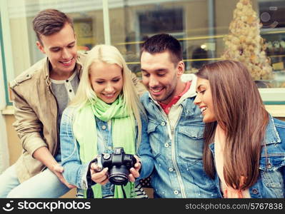 travel, vacation, technology and friendship concept - group of smiling friends with digital photocamera in the city