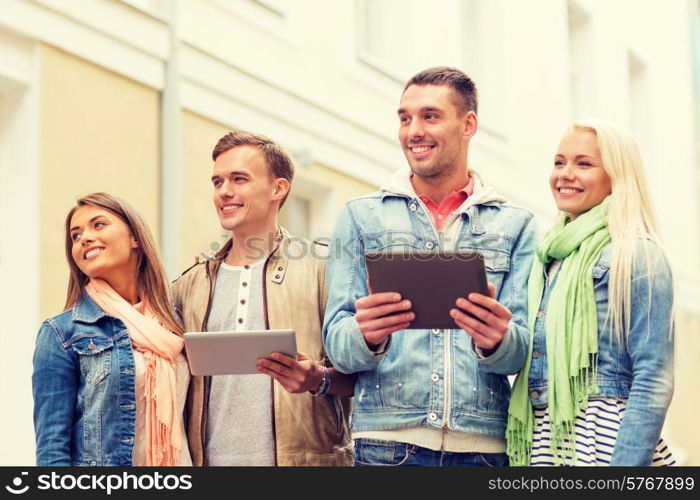 travel, vacation, technology and friendship concept - group of smiling friends with tablet pc computers in the city