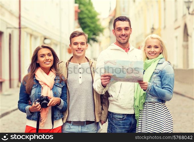 travel, vacation, technology and friendship concept - group of smiling friends with map and photocamera exploring city