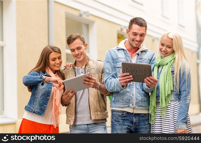 travel, vacation, technology and friendship concept - group of smiling friends with tablet pc computers in the city
