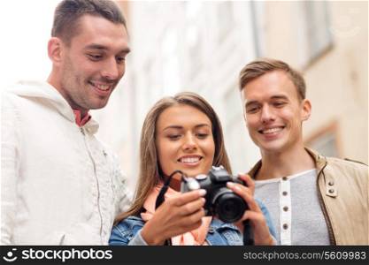 travel, vacation, technology and friendship concept - group of smiling friends with digital photocamera