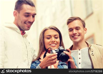 travel, vacation, technology and friendship concept - group of smiling friends with digital photocamera