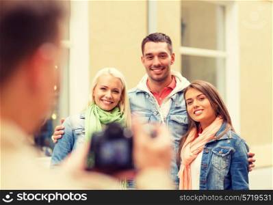 travel, vacation, technology and friendship concept - guy picturing group of friends in city