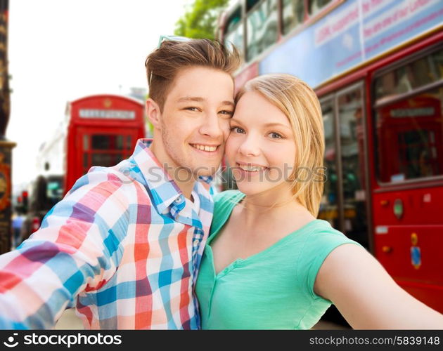 travel, vacation, technology and friendship concept - happy couple taking selfie over london city background