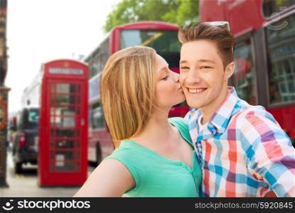 travel, vacation, technology and friendship concept - happy couple taking selfie over london city background