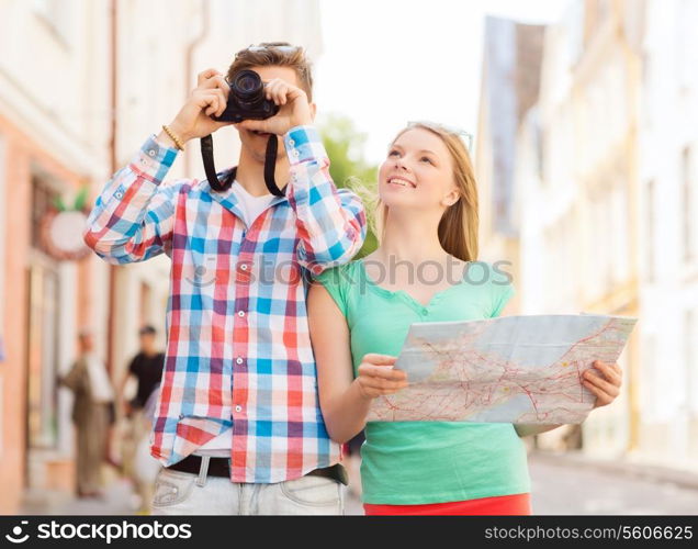 travel, vacation, technology and friendship concept - smiling couple with map and photo camera exploring city