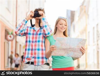travel, vacation, technology and friendship concept - smiling couple with map and photo camera exploring city